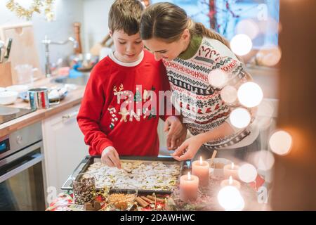 Mother and son decorating Christmas cookies on the sheet Stock Photo