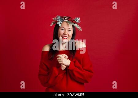 portrait of a happy laughing Asian young woman delighted with shopping or gift, on a red background Stock Photo