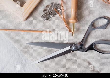 Knitting, handmade, handicraft hobby objects shot from above. Wood frame, macrame threads, needles and scissors in natural linen backdrop Stock Photo