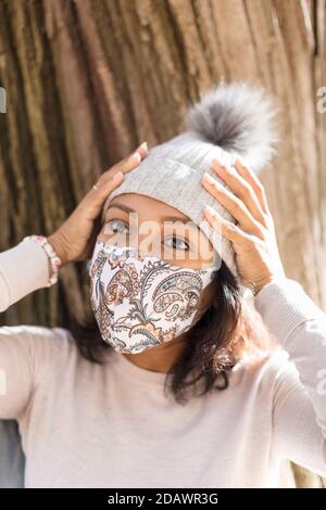 Portrait of young woman wearing a face mask. She is holding her hands to her head. Selective focus. Stock Photo