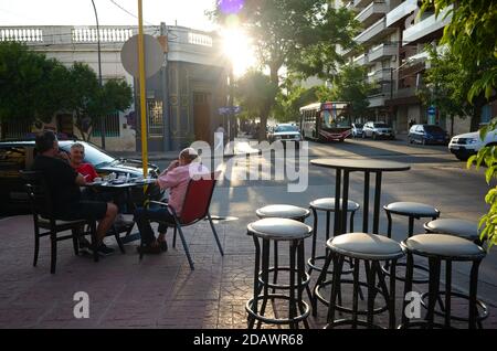 Cordoba, Argentina - January, 2020: Three men enjoying drinking coffee in cafe outside on the street on sunset. Stock Photo