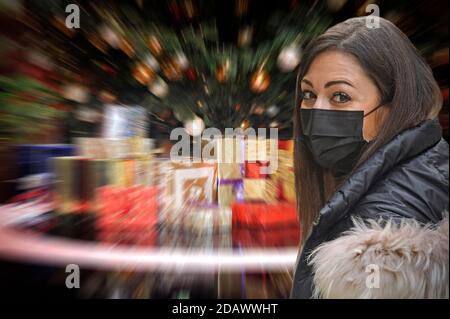 FOTOMONTAGE-Weihafterten 2020 in the middle of the coronavirus pandemic. What about the partial lockdown? Loosening of detainees will probably only be done with significantly decreasing corona numbers. Young woman with face mask, mask in front of Weihaftertsbaum, Weihaftertsbaum, Christmas tree, Christmas tree, Christmas tree, decorated, Christmas tree ball. Gifts, packages. | usage worldwide