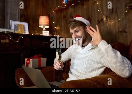 Happy young man waving hand celebrating virtual New Year party using laptop. Stock Photo