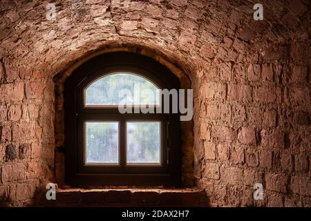 Brown window with an arch in a recess in the wall made of old red brick. From the window of the world series. Stock Photo