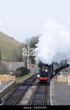 '30120' and 'Manston' double head through Corfe Castle as '30053' waits in the Up platform. Stock Photo