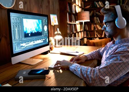 Male videographer editor using pc computer editing footage at home office. Stock Photo