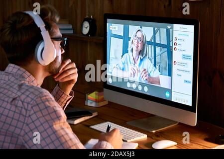 Male student wearing headphones taking online course seminar, watching webinar. Stock Photo