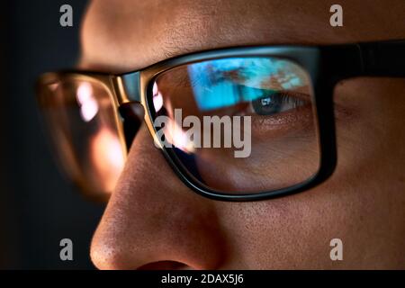 Close up view of focused businessman wear computer glasses looking at pc screen. Stock Photo