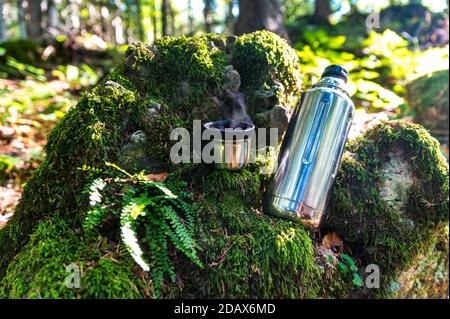 Close-up of steel thermos on moss covered stones Stock Photo