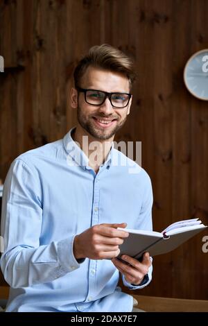 Smiling young business man holding planner looking at camera, portrait. Stock Photo