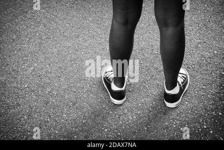 Black legs of the female protester during a manifestation of the 'black lives matter' movement - Millennial's feet wearing black canvas casual shoes o Stock Photo