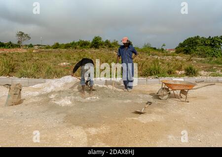 Standing And Looking At A Worker Mixing Mortar Stock Photo