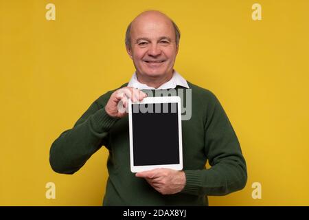 Senior aged middle aged man holding tablet with blank screen Stock Photo
