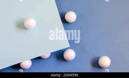 White balls on the blue paper background. Nice idea for trendy design. Top view, flat lay photo. Stock Photo