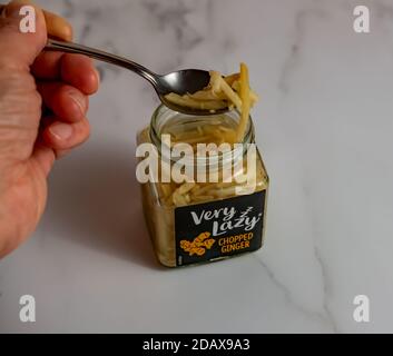 Norwich, Norfolk, UK – November 15 2020. Illustrative editorial photo of an Unidentifiable human hand holding a spoon with a glass jar of Vey Lazy cho Stock Photo