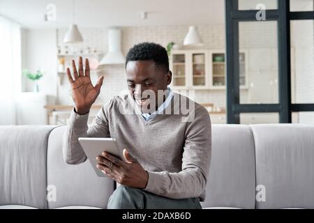 African american man waving hand video calling on digital tablet at home. Stock Photo