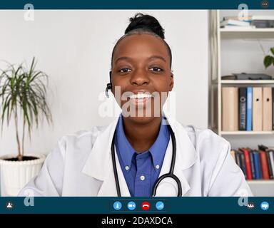 African female doctor talking to web camera, telemedicine video call. Stock Photo