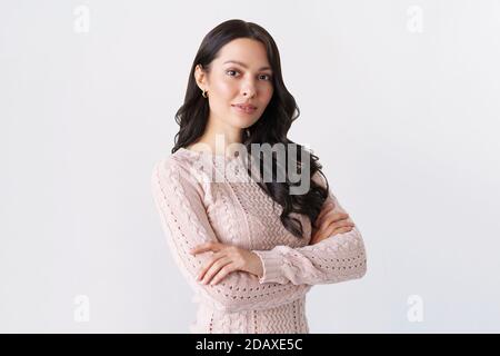 Young woman portrait. Adorable brunette in a sweater looking at the camera with her arms crossed. Stock Photo