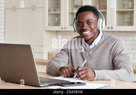 African business man student wearing headphones elearning at home office. Stock Photo