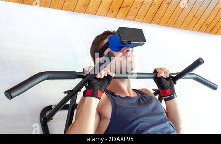 young man smiling enjoying virtual reality while doing sit-ups on a fixed drawbar at home Stock Photo