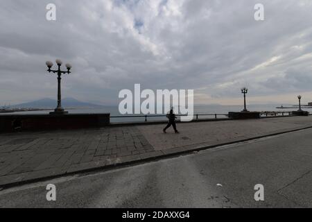Naples, Italy. 15th Nov, 2020. A man wearing protective mask walks on the seafront. From 15 November Campania Region is in the red zone with the highest level of restrictions to top the spread of Covid-19 disease. Credit: Independent Photo Agency/Alamy Live News Stock Photo