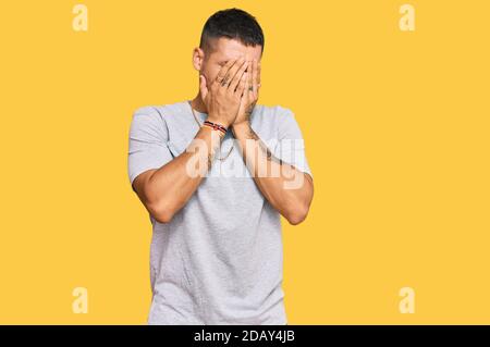 Handsome man with tattoos wearing 90s style with sad expression covering face with hands while crying. depression concept. Stock Photo