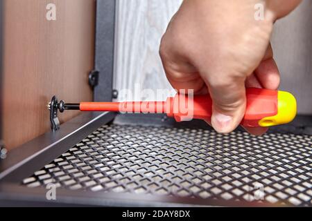 Worker tightens bolts while assembling flat pack furniture. Stock Photo
