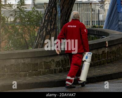 Napoli, Italy. 15th Nov, 2020. P.S. Cotugno hospital in emergency from Covid. The situation in front of the Cotugno Hospital at the first light of dawn is very calm, after the images of the previous days.Red Cross volunteer, carrying an oxygen cylinder. (Photo by Alessandro Barone/Pacific Press) Credit: Pacific Press Media Production Corp./Alamy Live News Stock Photo