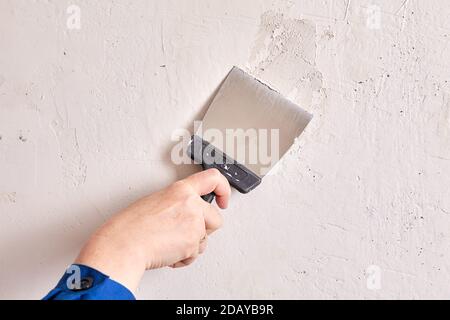 Handyman fills holes in wall with stucco and working tool. Stock Photo