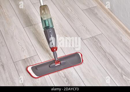 Cleaning lady cleans flat using mop with microfiber cloth and special liquid. Stock Photo