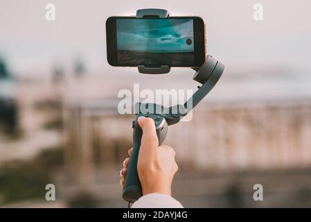 Woman hand with a gimbal for smartphone. Taking a photo of the sky. Stock Photo