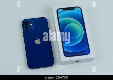 iPhone 12 in blue next to its box. Stock Photo