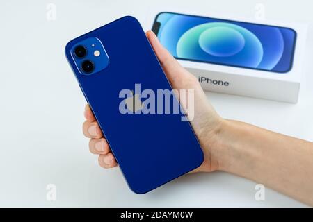 iPhone 12 in blue next to its box. Stock Photo