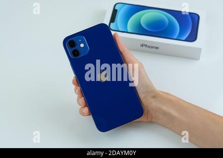 iPhone 12 in blue next to its box. Stock Photo