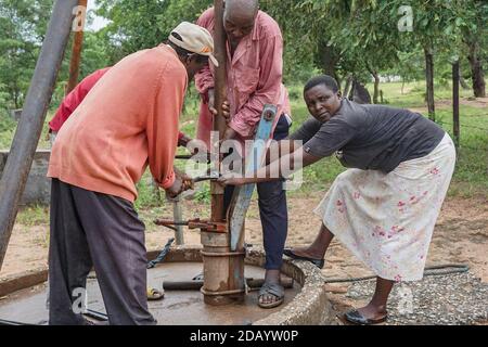 Primrose Masiyakurima (right) and other community members repair a broken borehole in Dora Ward 35, located in Zimbabwe’s Mutare District. Stock Photo