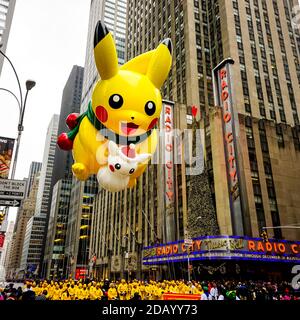 Pikachu pokemon balloon floats in the air during the Macy's Thanksgiving Day parade along Avenue of Americas with Radio Music Hall in the background. Stock Photo