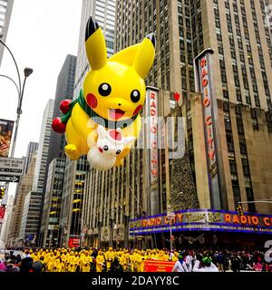 Pikachu pokemon balloon floats in the air during the Macy's Thanksgiving Day parade along Avenue of Americas with Radio Music Hall in the background. Stock Photo