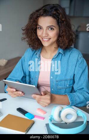 Vertical portrait of hispanic young woman using tablet and looking at camera. Stock Photo