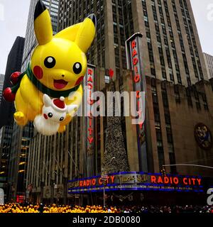 Pikachu pokemon balloon floats in the air during the Macy's Thanksgiving Day parade along Avenue of Americas with Radio Music Hall in the background. Stock Photo