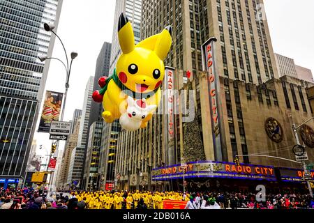 Pikachu pokemon balloon floats in the air during the Macy's Thanksgiving Day parade along Avenue of Americas with Radio Music Hall in the background. Stock Photo