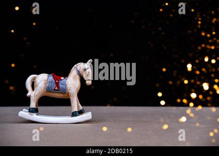 Christmas toy horse on black background with blurred lights. Copy space. Front view. Holiday christmas concept. Stock Photo