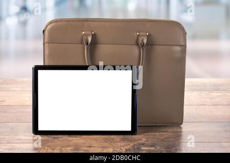Mock Up Digital Tablet pc With blank screen. Workspace with Bag, business briefcase, mockup blank digital tablet on wooden office table Stock Photo