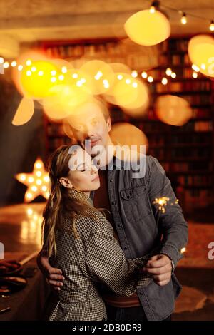 Lovely couple cuddling at home, charming husband hold sparklers, enjoy festive mood, cozy winter holidays, New Year and Christmas celebration concept Stock Photo