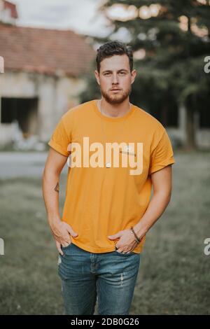 Vertical shot of a young Caucasian man with blonde hair wearing an orange shirt Stock Photo