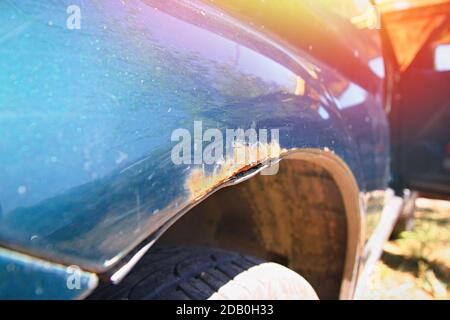 Detail of a rusty fender of a green car. Neglected care of the vehicle and the result of salt on winter roads Stock Photo