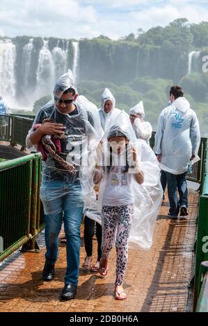 Visitors wearing bought plastic macs from the spray caused by the nearby waterfalls on the walkway on the Brazilian side  of the Iguazu Waterfalls i Stock Photo