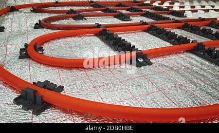 Installation of underfloor heating pipes on a heat reflecting membrane Stock Photo