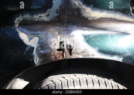Metal corrosion on a car fender, rust hole. car body repair. Front view Stock Photo
