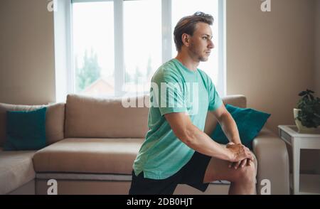 Blonde caucasian man is having a fitness session at home wearing sportswear Stock Photo