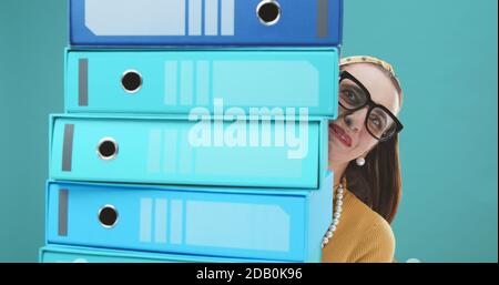 Desperate secretary holding a pile of folders, stressful job concept Stock Photo